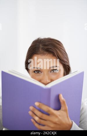 Das ist eine interessante Lektüre. Nahaufnahme einer lächelnden jungen Frau, die ihr Buch liest. Stockfoto