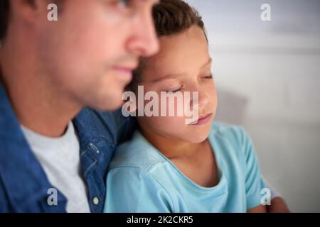 Sicher in den Armen von Daddys. Aufnahme eines Vaters, der sich zu Hause um seinen kranken kleinen Jungen kümmert. Stockfoto