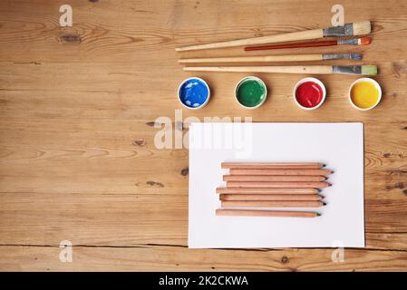 Bereiten Sie sich darauf vor, kreativ zu sein. Leeres Papier mit Malutensilien auf einem Holztisch. Stockfoto