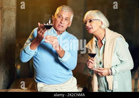 Es ist das perfekte Glas Wein. Eine kleine Aufnahme eines älteren Ehepaares, das eine kleine Weinprobe genießt. Stockfoto