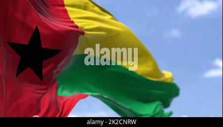 Detail der Nationalflagge von Guinea-Bissau, die an einem klaren Tag im Wind winkt. Stockfoto