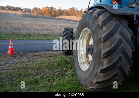 Nahaufnahme des blauen Traktorreifens mit Landwirtschaftsfeldhintergrund Stockfoto
