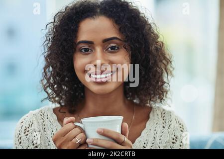 Es gibt nichts Besseres als Kaffee auf der Couch. Aufnahme einer attraktiven jungen Frau, die zu Hause eine Tasse Kaffee genießt. Stockfoto