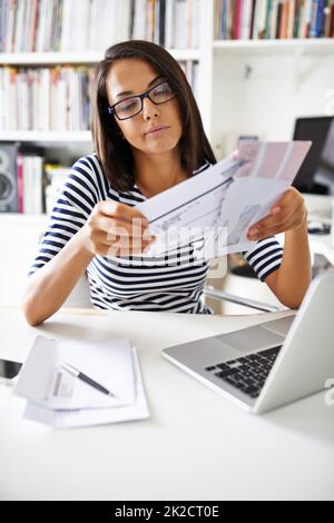 Finanzen in Ordnung bringen. Eine kurze Aufnahme einer attraktiven jungen Frau, die in ihrem Arbeitszimmer Rechnungen durchläuft. Stockfoto