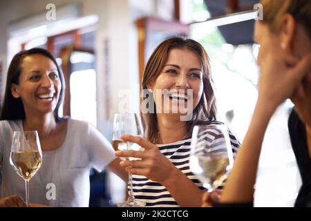 Die Mädchen feiern mit einem Glas Wein. Eine kurze Aufnahme von drei Frauen, die ein Glas Weißwein genießen. Stockfoto