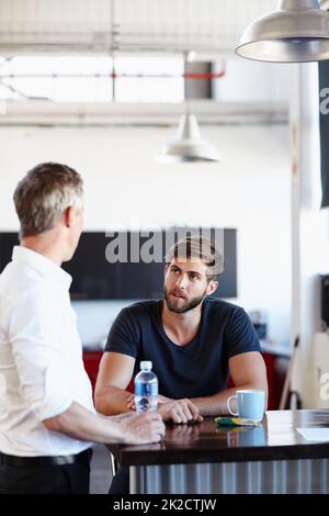 Während der Pause. Aufnahme von zwei gutaussehenden Geschäftsleuten, die im Büro eine Diskussion führen. Stockfoto