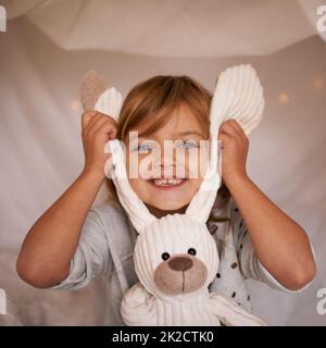 Mein lustiger Hase. Porträt eines entzückenden kleinen Mädchens, das spielerisch ihr Spielzeug-Kaninchen hält. Stockfoto