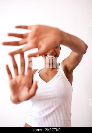 Shes ein wenig schüchtern. Studioaufnahme einer unkenntlichen Frau, die sich hinter ihren Händen versteckt. Stockfoto