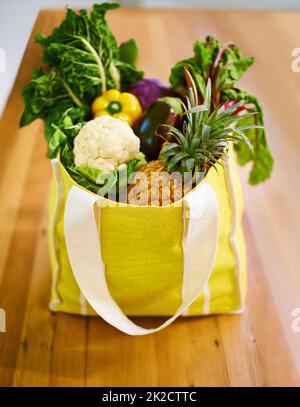 Ich habe eine Tüte voller Güte bekommen. Aufnahme einer Auswahl an Obst und Gemüse in einer Einkaufstasche. Stockfoto