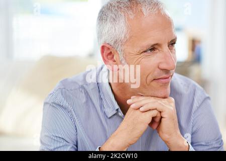 Das waren die guten Zeiten. Aufnahme eines reifen Mannes, der tief in Gedanken auf seinem Sofa sitzt. Stockfoto