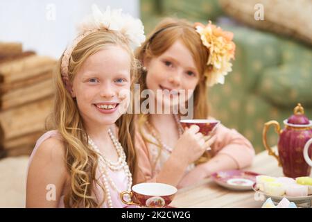 Die Teestunde. Zwei Freunde kleiden sich und feiern draußen im Garten eine Teeparty. Stockfoto