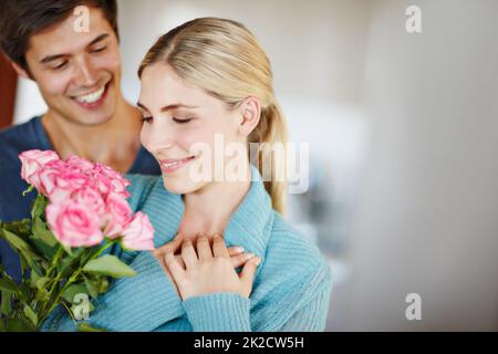 Gib ihr Rosen nur weil. Aufnahme eines liebevollen jungen Mannes, der seiner schönen jungen Frau einen Strauß rosa Rosen gab. Stockfoto