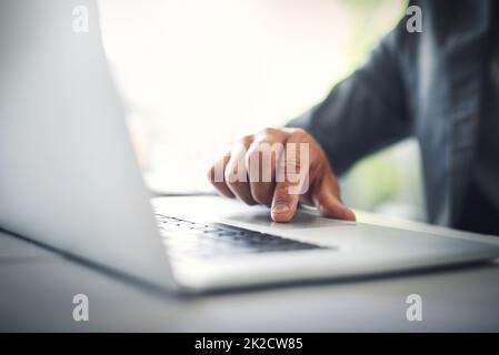 Er hat einen vertrauenswürdigen Laptop. Aufnahme eines unerkennbaren Geschäftsmannes, der tagsüber im Büro an seinem Laptop arbeitet. Stockfoto