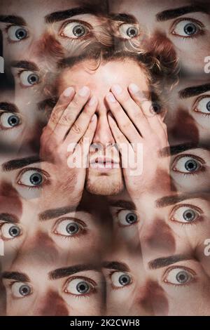 Sie beobachten immer. Ein junger Mann mit den Händen vor den Augen, umgeben von vielen Augen. Stockfoto