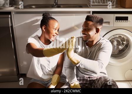 Kein Chaos, kein Stress. Aufnahme eines jungen Paares, das sich gegenseitig eine hohe fünf gab, nachdem es zu Hause gemeinsam Aufgaben erledigt hatte. Stockfoto