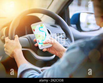 GPS wird den Weg finden. Ausgeschnittene Aufnahme einer Frau, die das gps-System ihres Handys benutzt, während sie ein Auto fährt. Stockfoto