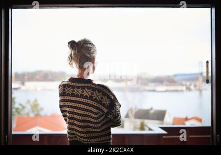 Die Aussicht genießen. Rückansicht einer Frau, die aus dem Fenster schaute. Stockfoto