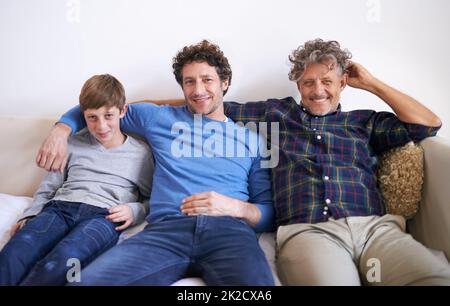 Einnahme nach einander. Porträt von drei Generationen von Männern, die zu Hause auf einem Sofa sitzen. Stockfoto