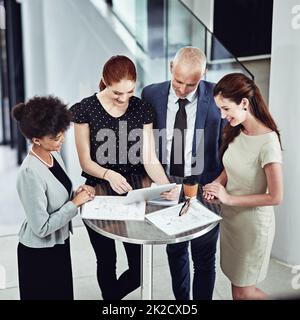 Geschäftsbesprechung über eine neue App ausführen. Aufnahme eines Geschäftsteams eines Unternehmens, das bei einem Meeting bei der Arbeit ein digitales Tablet verwendet. Stockfoto