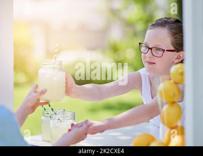 Los geht's - viel Spaß! Ein kurzer Schuss eines kleinen Mädchens, das Limonade von ihrem Stand draußen verkauft. Stockfoto