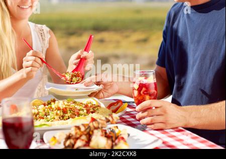 Essen ist der Weg in das Herz eines menschen. Zugeschnittenes Bild eines jungen Paares, das draußen eine Mahlzeit isst. Stockfoto