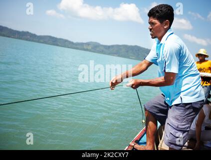 Toller Fang. Thailändischer Fischer zieht einen Haul auf seinem Fischerboot ein - Copyspace. Stockfoto