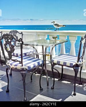 Urlaub am Ufer. Tische und Stühle auf dem Balkon eines Restaurants am Meer. Stockfoto