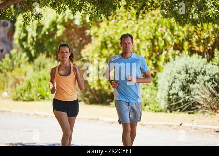 Wenn nichts richtig geht, Lauf. Aufnahme eines glücklichen Paares, das in ihrer Nachbarschaft zusammen joggt. Stockfoto