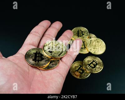 bitcoin-Münze auf der Hand auf schwarzem Hintergrund platziert Stockfoto