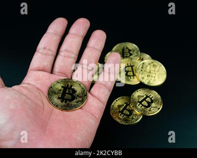 bitcoin-Münze auf der Hand auf schwarzem Hintergrund platziert Stockfoto