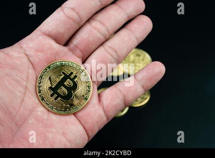 bitcoin-Münze auf der Hand auf schwarzem Hintergrund platziert Stockfoto