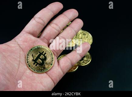 bitcoin-Münze auf der Hand auf schwarzem Hintergrund platziert Stockfoto