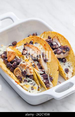 Tacos gefüllt mit gegrilltem Hähnchenfleisch, roten Bohnen und geriebenem Käse Stockfoto