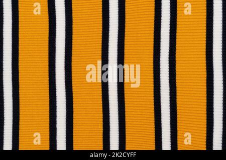 Hintergrund eines gelben Strickpulvers mit weißen und schwarzen Streifen Stockfoto