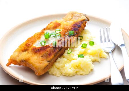 Gebratener Fisch mit Kartoffelpüree und Frühlingszwiebeln Stockfoto