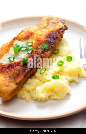 Gebratener Fisch mit Kartoffelpüree und Frühlingszwiebeln Stockfoto