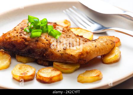 Karpfen auf Kreuzkümmel mit gebratenen Kartoffeln Stockfoto