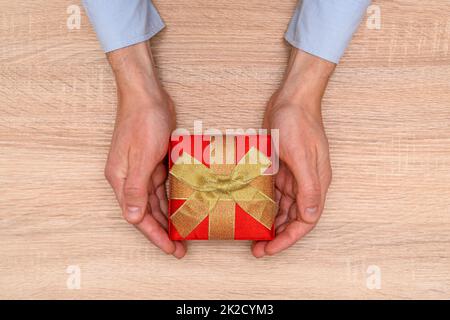 Hände halten Geschenk oder Geschenkbox mit goldener Schleife Stockfoto