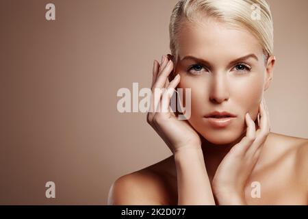 Seidig weiche Haut. Beauty-Aufnahme einer jungen blonden Frau, die ihr Gesicht berührt. Stockfoto