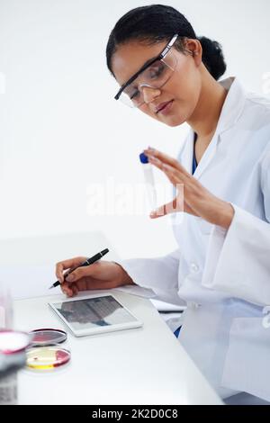 Korrelation der Daten. Ausgeschnittene Aufnahme einer attraktiven jungen Wissenschaftlerin, die in ihrem Labor arbeitet. Stockfoto