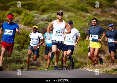 Das Tempo bestimmen. Aufnahme einer Gruppe junger Männer, die einen Marathon laufen. Stockfoto