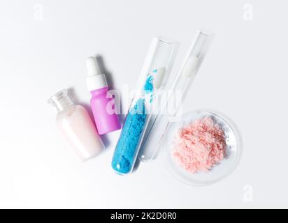 Pflegecreme, Serum, Kupfer(II)-Sulfat im Reagenzglas und himalaya-Rosa-Salz. Chemikalien für die Schönheitspflege auf weißem Labortisch. (Draufsicht) Stockfoto