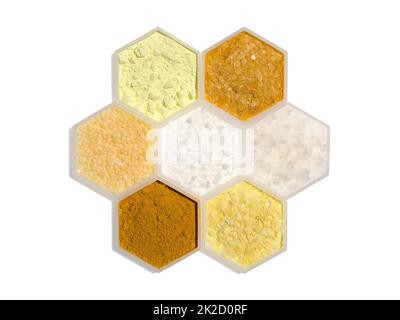 Chemischer Inhaltsstoff in hexagonalem molekularförmigem Behälter. Schwefelpulver, Carnaubawachs, Candelillawachs, Cetyl Esters Wax, Flake Salz, Curcuma-Pulver und Natriumsulfid-Flocken. Stockfoto