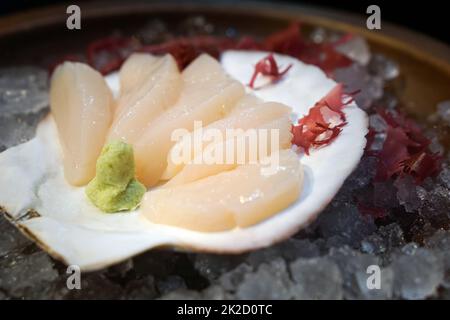 Das Hotate Sashimi Set ist wunderschön auf Eis arrangiert und mit einer großen Schale dekoriert. Stockfoto