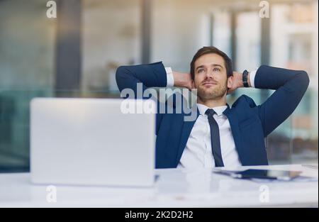 Er lässt das Geschäft einfach aussehen. Aufnahme eines jungen Geschäftsmannes, der entspannt mit den Händen hinter dem Kopf aussieht. Stockfoto