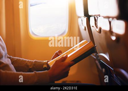 Lesen ist eine Möglichkeit für Ihre Fantasie, um zu fliegen. Aufnahme eines Passagiers, der ein Buch in einem Flugzeug liest. Stockfoto