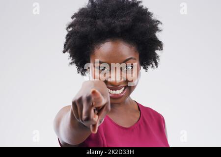 Du bist der nächste auf meiner Liste. Porträt einer schönen jungen Frau, die vor grauem Hintergrund auf die Kamera zeigt. Stockfoto