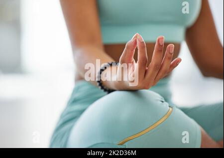 Frieden in mir selbst finden. Ausgeschnittene Aufnahme einer unkenntlichen Frau, die allein in einem Yoga-Studio meditiert. Stockfoto