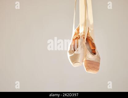 Alles Ballett ist Tanz, aber nicht jeder Tanz ist Ballett. Aufnahme eines Paares auf Ballettschuhen, die in einem Tanzstudio hängen. Stockfoto