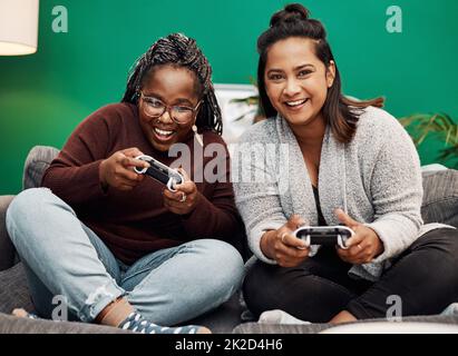 Girls Night-in für die Gaming-Fanatiker. Aufnahme von zwei jungen Frauen, die zu Hause Videospiele auf dem Sofa spielen. Stockfoto
